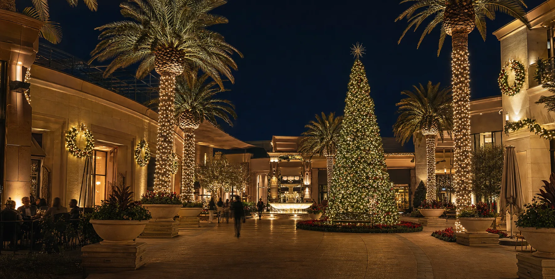 Shopping plaza with illuminated palms and a large Christmas tree